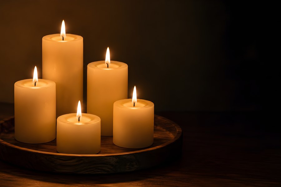 Five Lit Pillar Candles Glowing Warmly on a Wooden Tray in a Dark Cozy Room