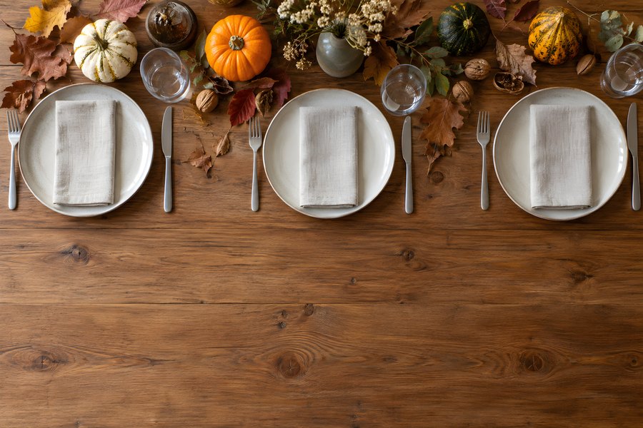 Overhead autumn table setting with pumpkins, walnuts, dried flowers and rustic wooden copy space