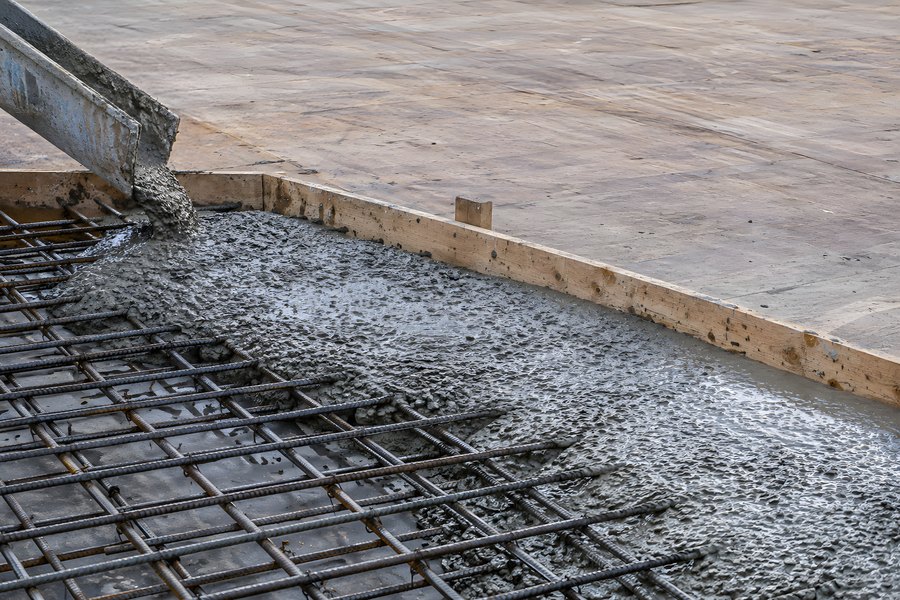 Wet Concrete Pouring from a Chute onto Steel Rebar Mesh Within Timber Slab Formwork
