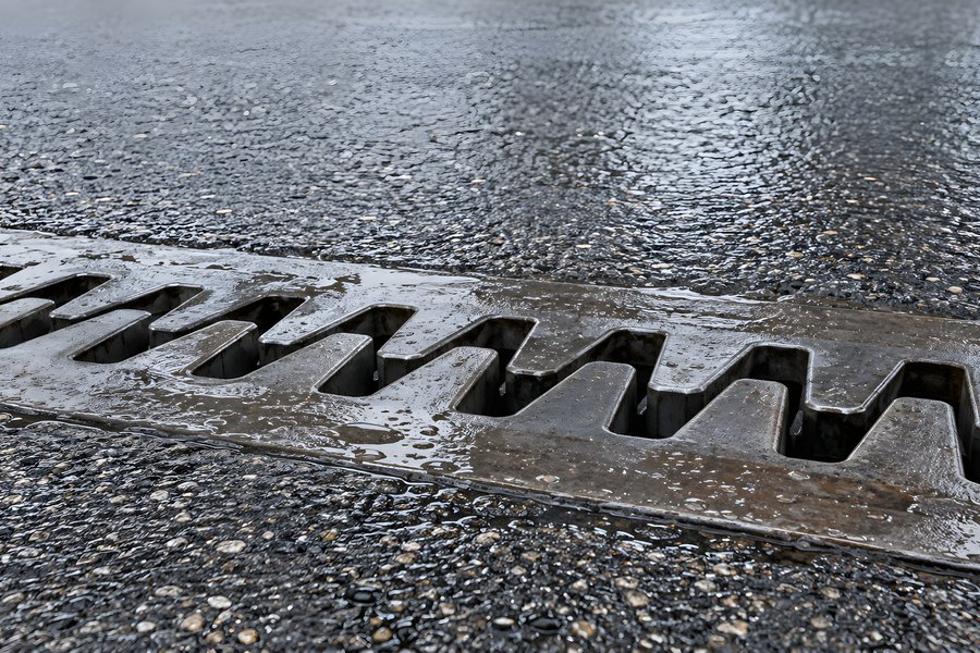 Zigzag steel expansion joint embedded in wet asphalt road with rain reflections and exposed aggregate texture