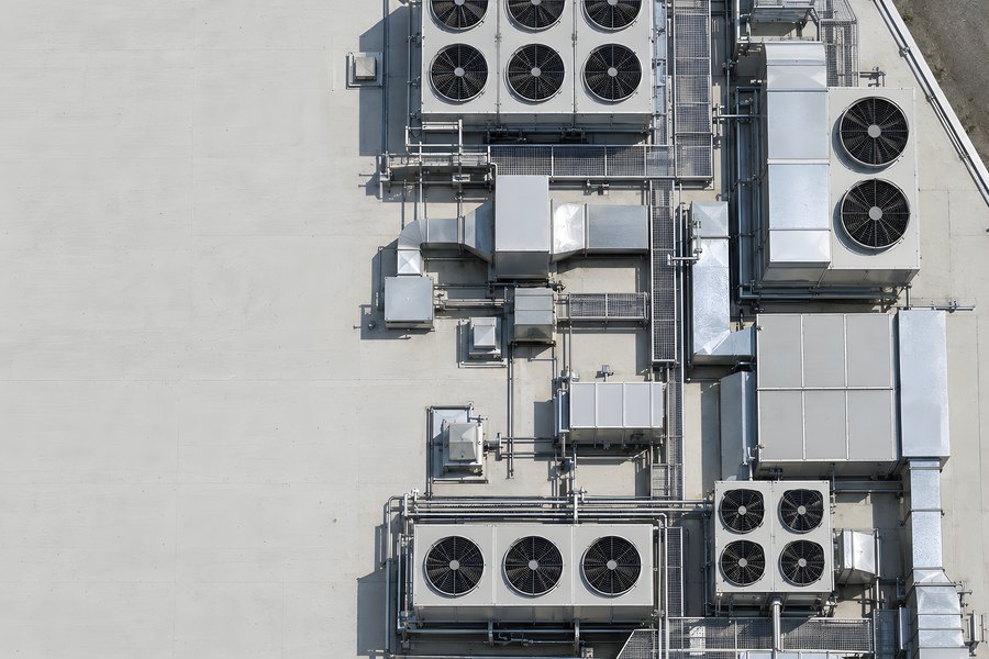 Aerial top-down view of a data center rooftop showing cooling units, fans, ductwork and pipework