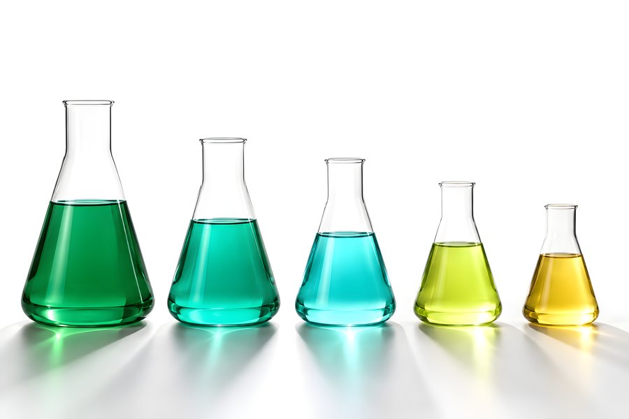 Five Erlenmeyer flasks filled with green to amber colored liquid in graduated sizes on a white background