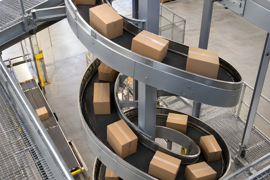 Spiral conveyor belt system moving cardboard boxes through an automated warehouse, high-angle view with no people