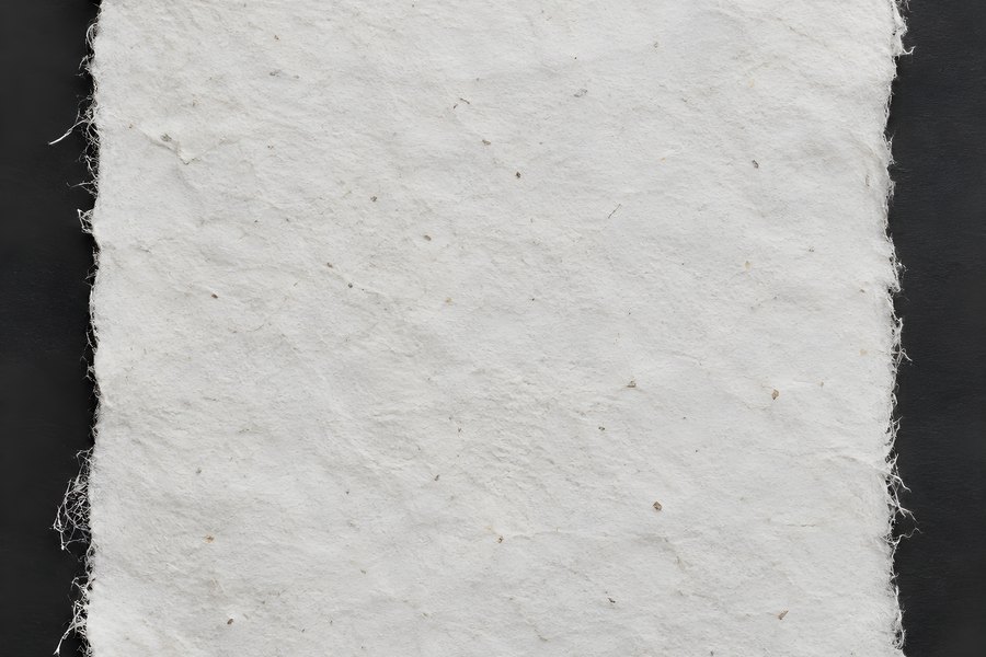 Handmade Paper Sheet with Torn Deckle Edges and Visible Fibres on a Dark Background