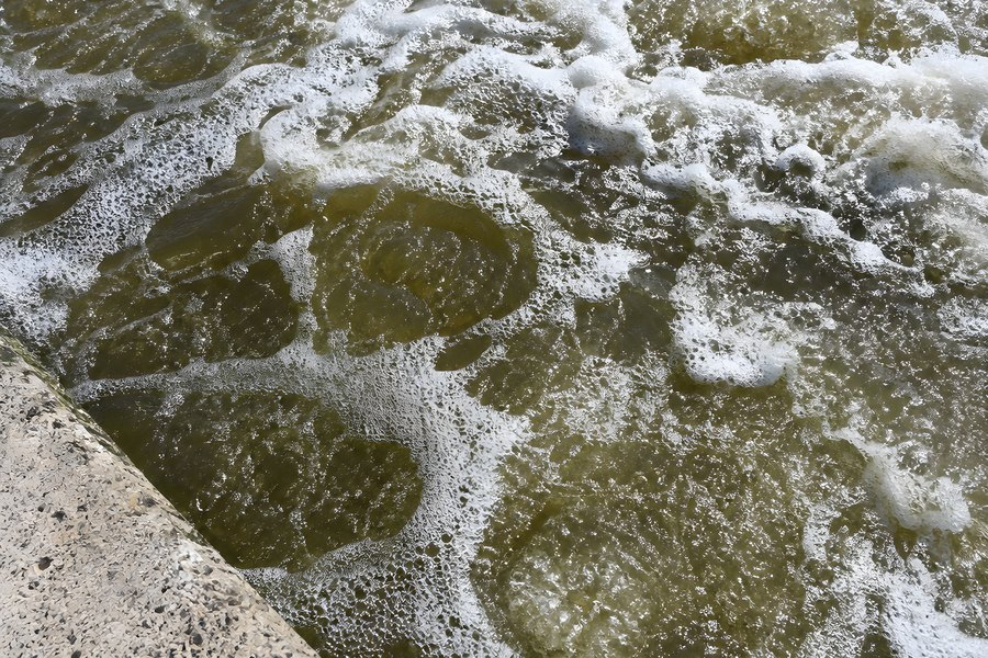 Overhead View of Foamy Turbulent Water Along a Concrete Tank Edge at a Wastewater Treatment Facility