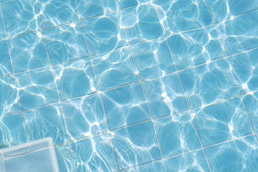 Turquoise Swimming Pool Water Surface with Sunlight Caustics Rippling Over a Tiled Floor