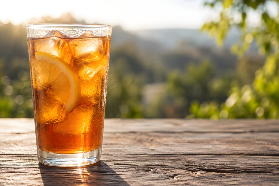 Iced Tea Glass with Lemon Slices and Condensation on a Rustic Wooden Table at Sunset