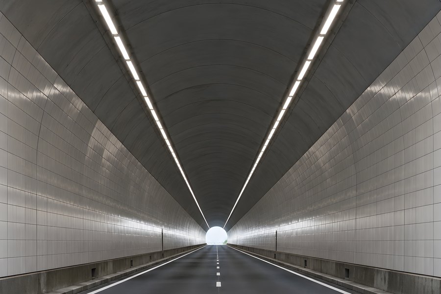 Empty road tunnel with converging light strips leading to a bright vanishing point