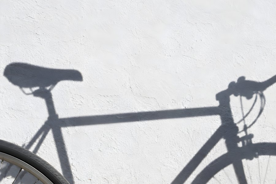 Bicycle Wheel and Its Shadow Cast Across a Textured White Wall